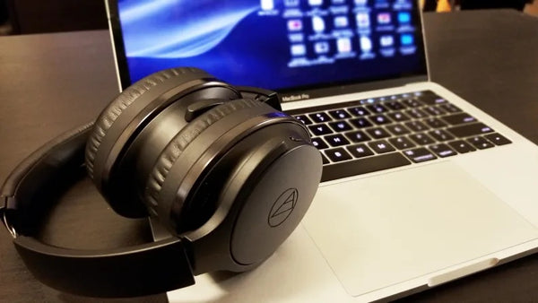 An open laptop with some black headphones resting on it