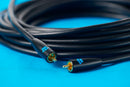 Coiled black audio cable with gold connectors on a blue background